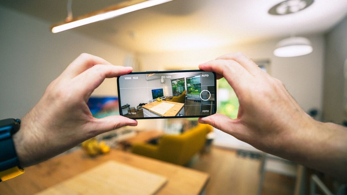Mâini care fotografiază o cameră cu telefonul